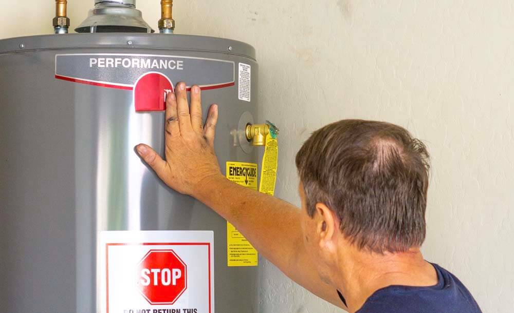 Plumber checking newly replaced water heater by touching the outside with his hand