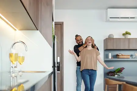 Man leading wife by coverin her eyes to see new kitchen remodel